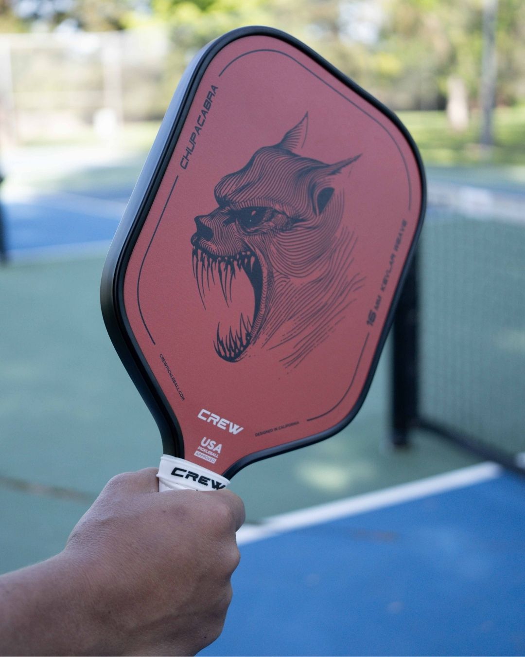 Player holding the Chupacabra pickleball paddle by Crew Pickleball, featuring a bold monster graphic and 16mm kevlar weave core for unmatched control and precision on the court.