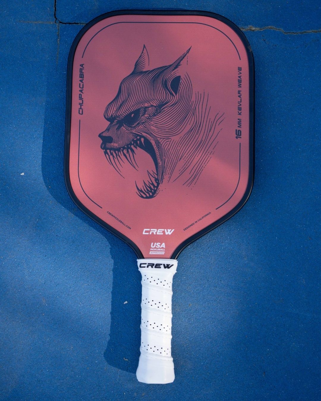 Close-up of the Chupacabra pickleball paddle by Crew Pickleball, featuring a 16mm kevlar weave core for elite control and an aggressive graphic design on a textured red face.